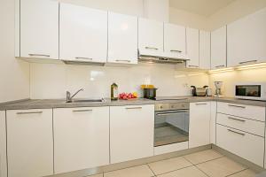 a white kitchen with white cabinets and a sink at Torbole Relax, Pool & Balcony Apartment in Nago-Torbole