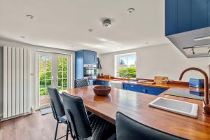 a kitchen with a wooden table and blue cabinets at John Brown Cottage in Skipton