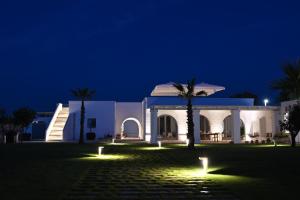 a white building with a palm tree in front of it at Corte di Torre Spaccata in Torre Canne