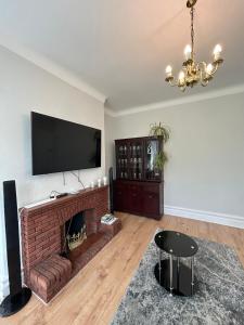 a living room with a fireplace and a flat screen tv at Bella Beach House in Whitley Bay