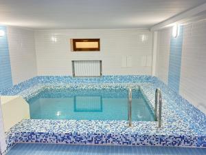 a bathroom with a large tub with blue tiles at Green Hill Hotel in Almaty