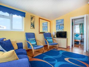a living room with blue chairs and a blue couch at Skylarks in Saint Merryn