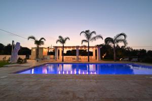 a swimming pool in front of a house with palm trees at Corte di Torre Spaccata in Torre Canne