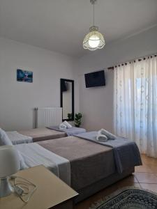 a bedroom with two beds and a tv and a table at Guest House KrisHen in Përmet