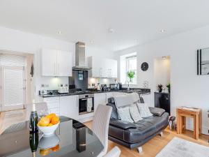 a kitchen and living room with a table and a couch at Gwendrock Diw in Looe