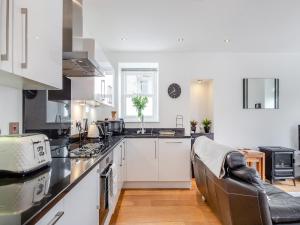 a kitchen with white cabinets and a couch in it at Gwendrock Diw in Looe