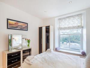 a bedroom with a bed and a mirror and a window at Gwendrock Diw in Looe