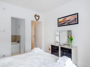 a white bedroom with a large bed and a bath tub at Gwendrock Diw in Looe +11 photos