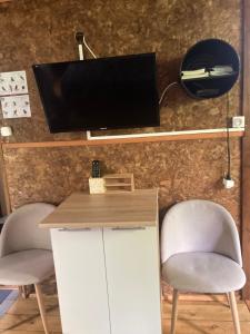 a desk with two chairs and a television on a wall at Eden des laves in Sainte-Rose