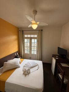 a bedroom with a large white bed with a ceiling fan at Pousada Contos de Minas in Mariana +56 photos