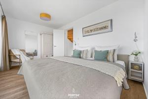 a white bedroom with a large bed with blue pillows at Ferienhaus Hamptons Beach House Olpenitz in Olpenitz