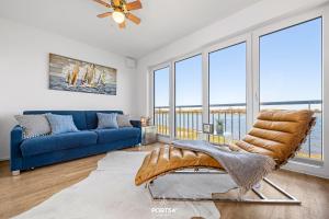 a living room with a blue couch and windows at Ferienhaus Hamptons Beach House Olpenitz in Olpenitz