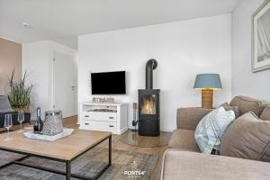 a living room with a couch and a fireplace at Ferienhaus Hamptons Beach House Olpenitz in Olpenitz +31 photos