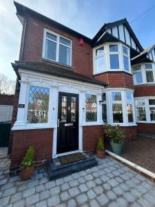 a red brick house with a black door at Bella Beach House in Whitley Bay