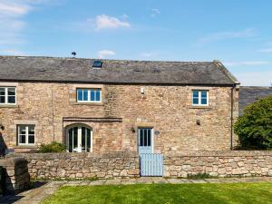 an old stone house with a stone wall at Murton Cottage in East Ord