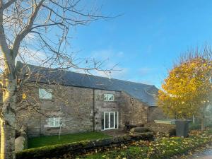 a stone house with a tree in front of it at Murton Cottage in East Ord