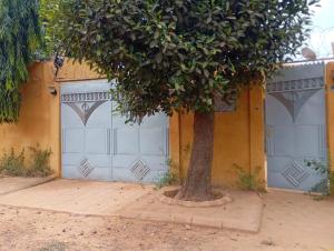 a tree in front of a building with two garage doors at RESIDENCE MEUBLEe BOBO LAFIA in Bobo-Dioulasso