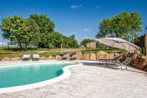 a swimming pool with chairs and an umbrella at Il Casale di Zoe in Sorano