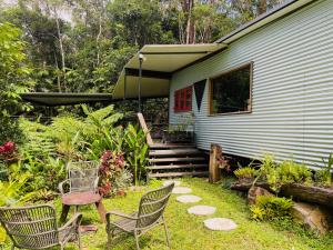a house with two chairs and a table and a porch at Sun Suite - tiny home treehouse in Kuranda