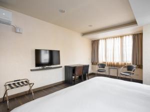 a hotel room with a bed and a flat screen tv at West Hotel in Puli