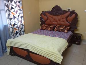 a bed with a wooden headboard with a blanket on it at RESIDENCE MEUBLEe BOBO LAFIA in Bobo-Dioulasso