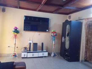 a living room with a flat screen tv and a room with flowers on the wall at RESIDENCE MEUBLEe BOBO LAFIA in Bobo-Dioulasso