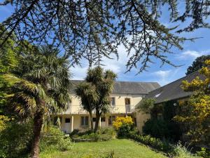 an exterior view of a house with palm trees at Logis Hôtel La Demeure du Perron in Quettehou