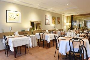 une salle à manger avec tables et chaises et nappes blanches dans l'établissement Logis Hôtel L'Auzeraie, à Ax-les-Thermes