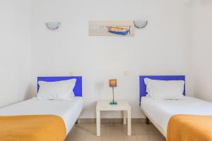 two twin beds in a room with a table at HI Lagos - Pousada de Juventude in Lagos +39 photos