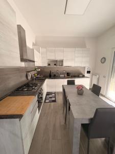 a large kitchen with white cabinets and a table at Susy's Home Appartamento in centro in Corchiano