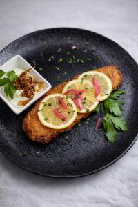 a plate with a piece of fish with lemon slices on it at Berghof Grüner Baum in Sasbachwalden +22 photos