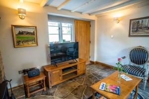 a living room with a television and a table at March Hare Cottage in Bretforton in Bretforton