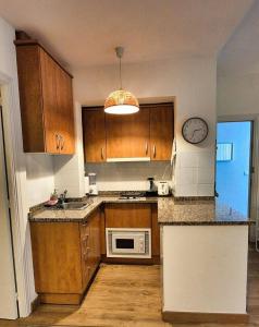 a kitchen with wooden cabinets and a clock on the wall at Les Flors !2minutos de la playa! in Lloret de Mar