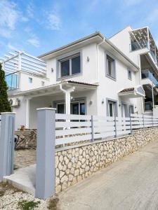 a white house with a stone fence at Villa Little John in Skala Rachoniou