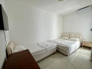 a white room with a bed and a table at Garden studio apartmans in Dobra Voda +40 photos
