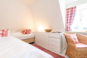 a bedroom with a bed and a chair and a window at Düünhuus in Hörnum