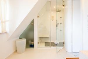 a bathroom with a walk in shower under a staircase at Düünhuus in Hörnum +29 photos