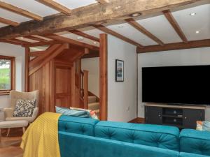 a living room with a blue couch and a flat screen tv at Pylemoor Cottage in Tiverton