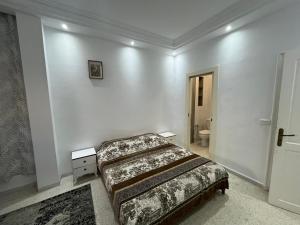 a bedroom with a bed in a white room at Cozy house in El Aouina Station