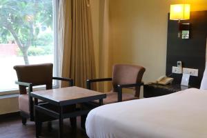 a hotel room with a bed and two chairs and a table at Orient Resorts in Kānpur
