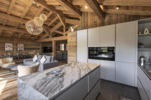 a kitchen with white cabinets and a living room at Chalet Suzane - Panorama Mont-Blanc & jacuzzi in Combloux
