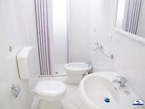 a white bathroom with a toilet and a sink at Le Fontanelle 2 in Fontanelle