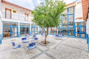 a courtyard with chairs and a tree in front of a building at HI Lagos - Pousada de Juventude in Lagos