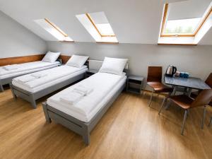 a room with two beds and a table and windows at Pokoje Noclegowe Sierpów in Sierpów