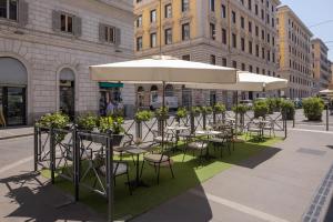 a group of tables and chairs under an umbrella on a street at UNA Hotels Decò Roma in Rome