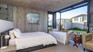 a bedroom with a large white bed and a balcony at Mi Amor Beach House in Sedgefield