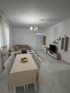 a dining room and living room with a table and chairs at Villa Kokoneshi in Divjakë +9 photos