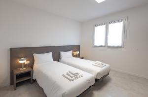 two beds in a room with white walls and a window at The Residence 2.0 in Galliate
