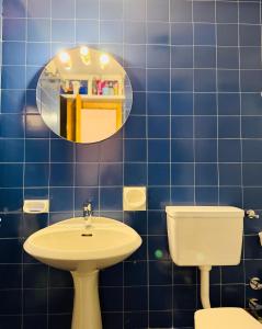 ein blau gefliestes Badezimmer mit Waschbecken und Spiegel in der Unterkunft Pila64 in Pila
