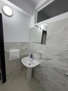 a white bathroom with a sink and a shower at Villa Kokoneshi in Divjakë
